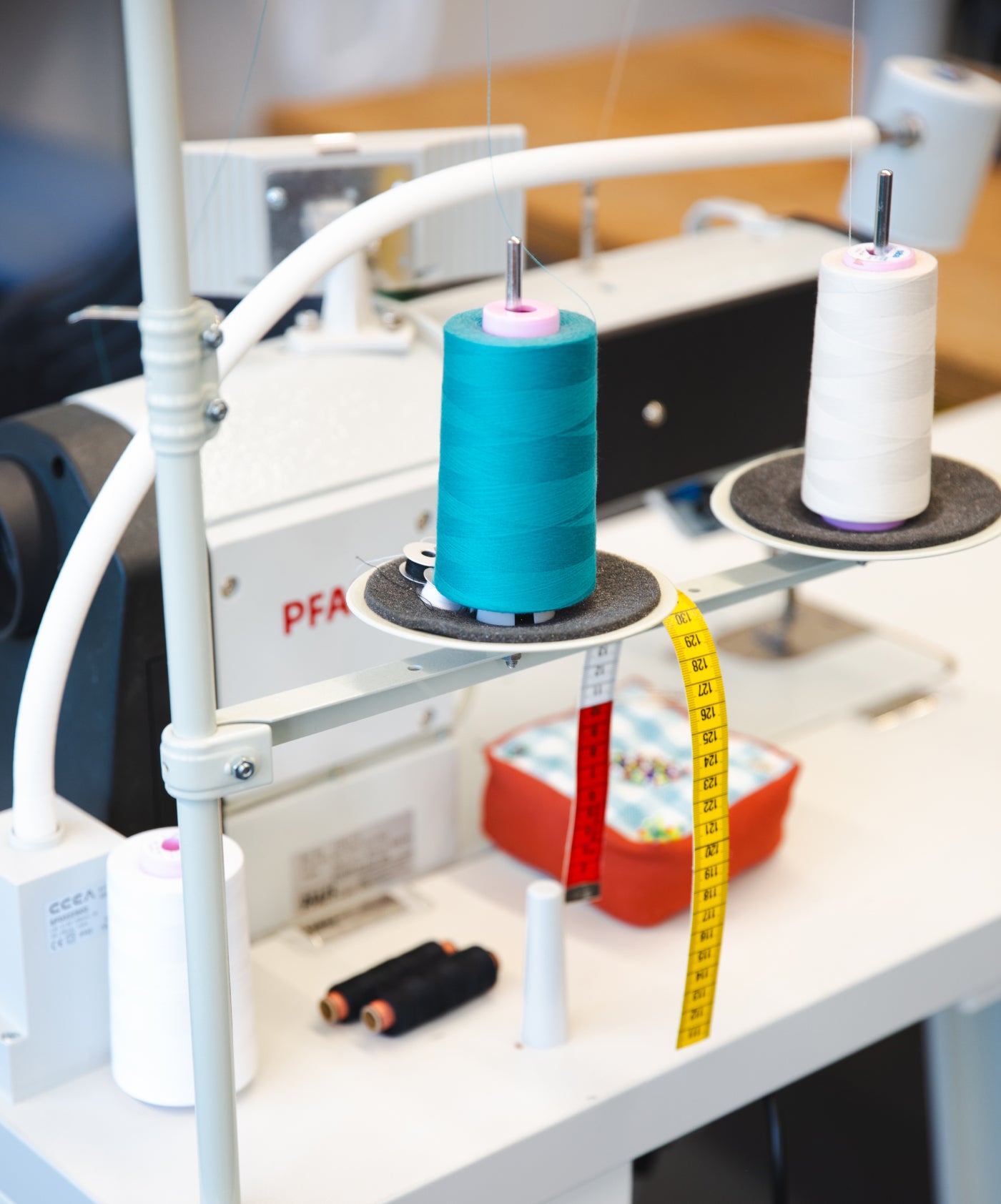 Nähplatz mit Nähmaschine, türkischer Fadenspule und Maßband.