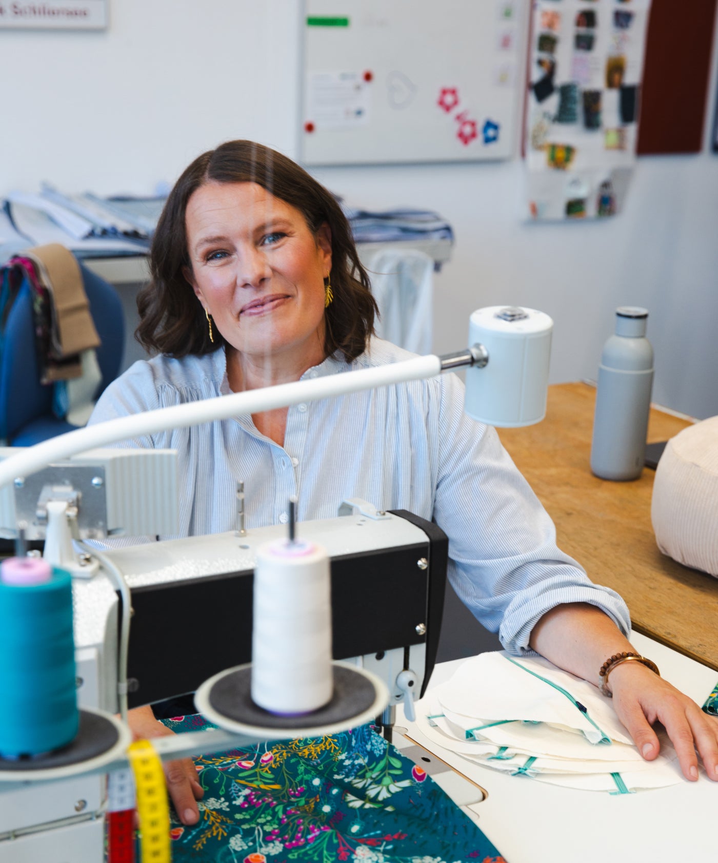 Frau sitzt hinter einer Nähmaschine und lächelt