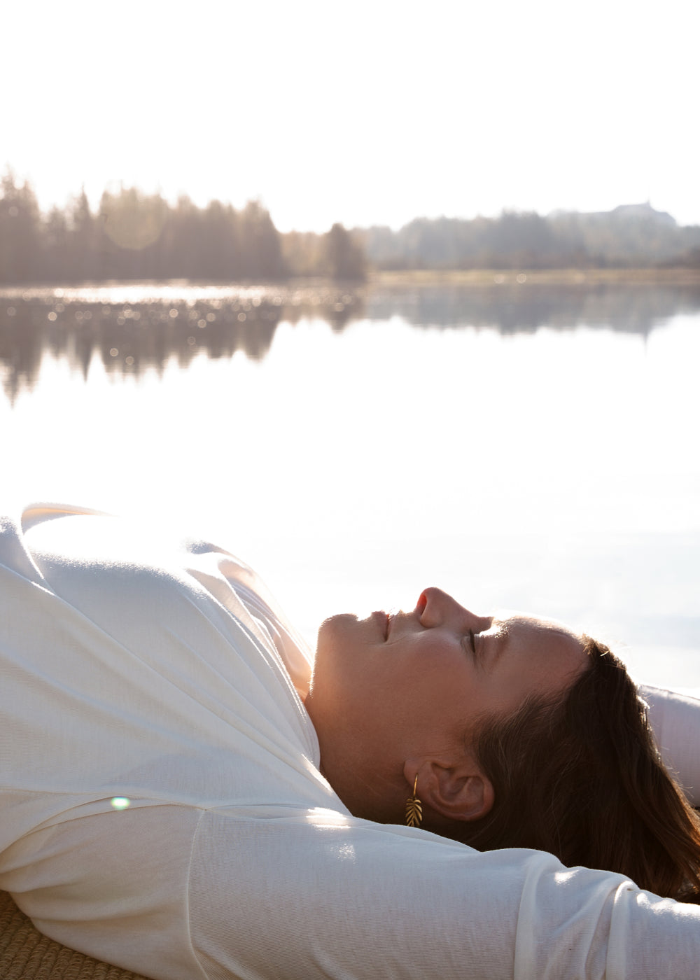 Eine Frau übt Yoga an einem See. im Hintergrund ist ein Wald.