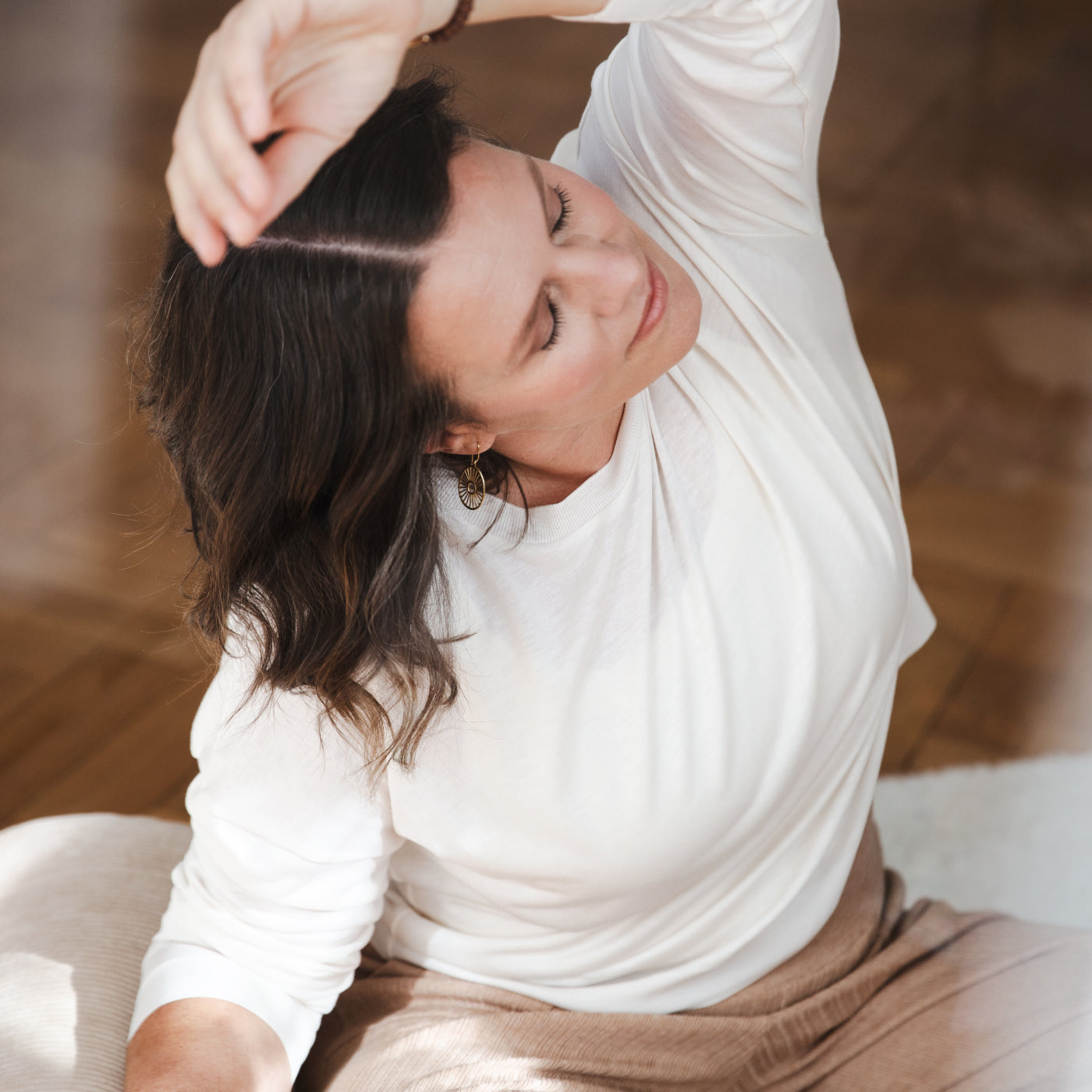 Eine Frau übt eine Seitbeuge im Yin Yoga auf einer weißen Yogamatte.